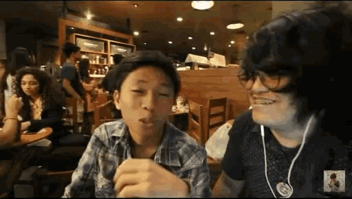 two boys are sitting at a table in a restaurant eating food