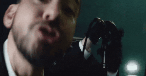 a close up of a man singing into a microphone
