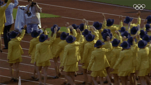 a group of people wearing yellow jackets and blue hats are raising their arms in the air