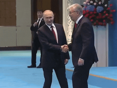 a man in a suit shakes hands with another man in a suit