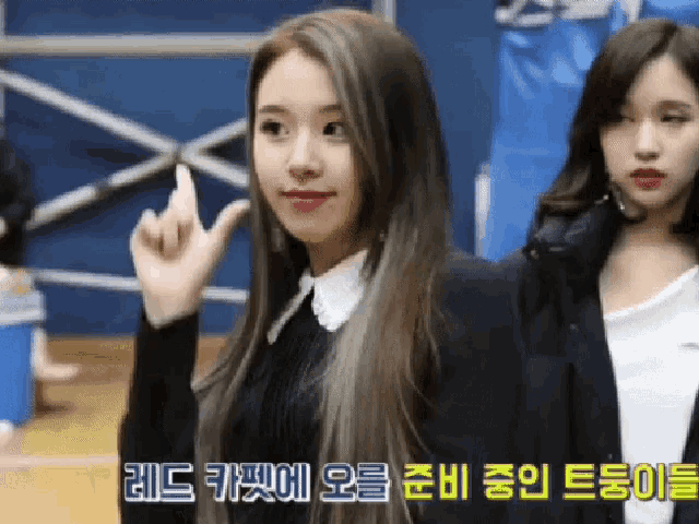 a woman with long hair is giving a thumbs up sign while standing next to another woman