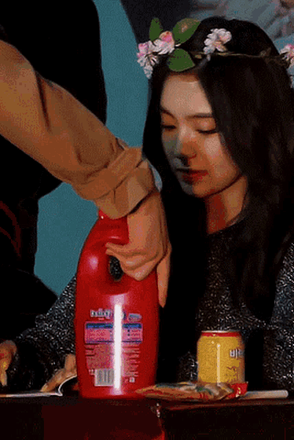 a woman with a flower crown on her head is holding a bottle of detergent