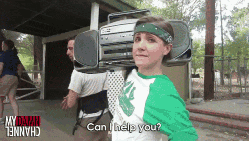 a girl is carrying a boombox on her shoulders and asking can i help you