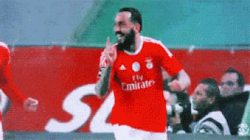 a soccer player wearing a fly emirates jersey is celebrating