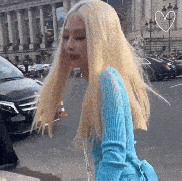 a woman with blonde hair wearing a blue sweater is walking down the street .