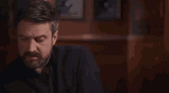 a man with a beard is sitting at a table with a knife and fork .