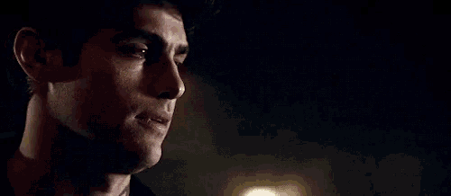 a close up of a man 's face in a dark room with a light behind him .