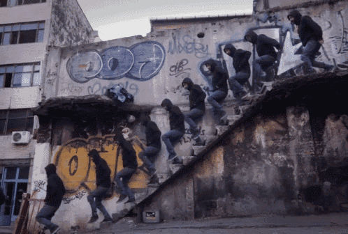 a group of people are jumping over a wall that has graffiti on it