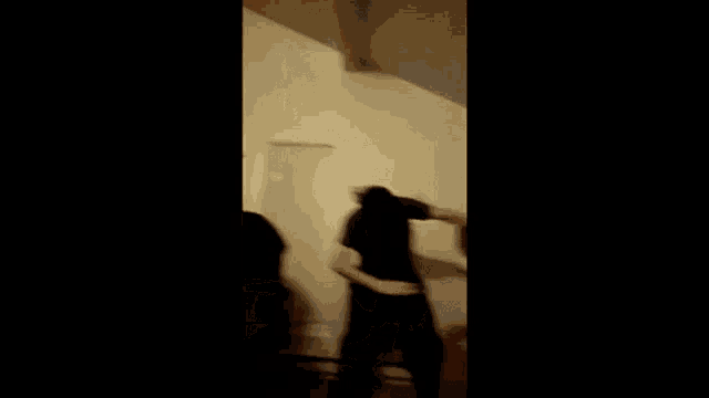a person is dancing in a dark room in front of a wall .