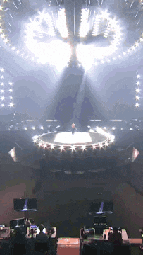 a man is standing on a stage with a circle of lights around him