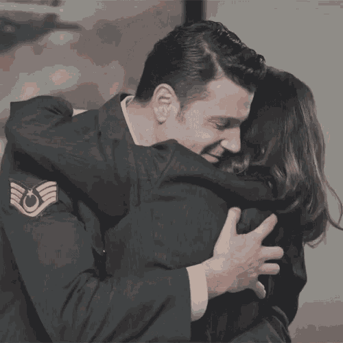 a man in a military uniform hugging a woman in a suit
