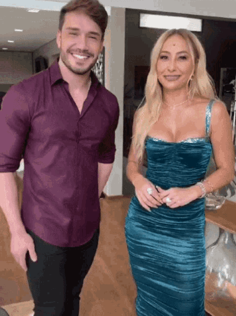 a man in a purple shirt and a woman in a blue dress are standing next to each other and smiling