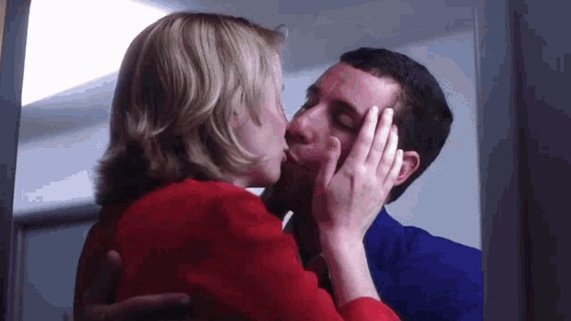 a man and a woman are kissing in a room