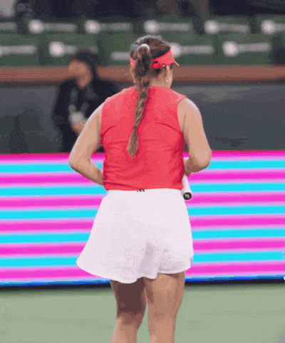 a woman in a red top and white shorts is standing on a tennis court