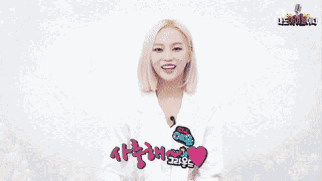 a woman wearing a white shirt with a heart on it is holding a microphone