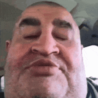 a close up of a man 's face with his eyes closed and his mouth open .