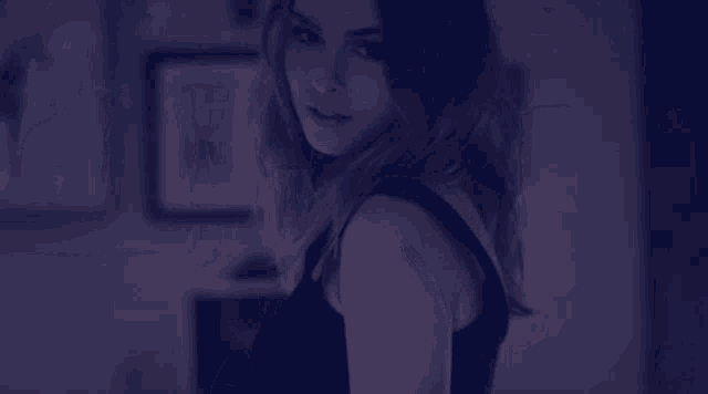 a woman in a black tank top looks at the camera