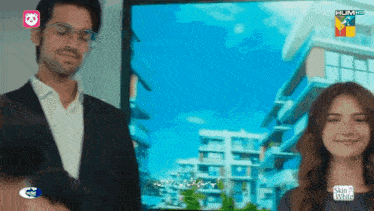 a man and a woman are standing in front of a screen that says hum hd on it