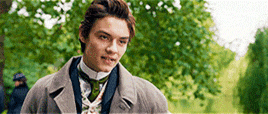 a young man is standing in a park wearing a suit and tie .