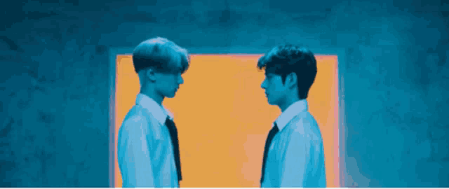 two men are standing next to each other and looking at each other in a blue and orange room .