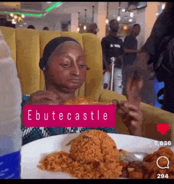 a woman is sitting at a table with a plate of food and a sign that says ebutecastle on it .