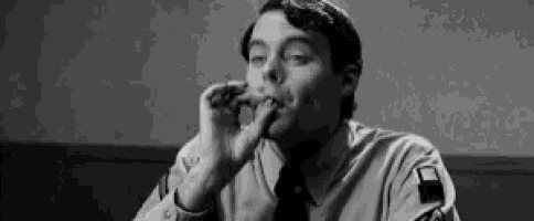 a man in a police uniform is smoking a cigarette while sitting at a table .