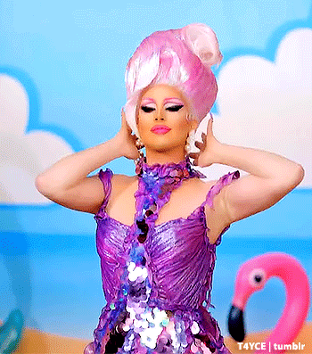 a drag queen wearing a purple sequined dress is standing in front of a pink flamingo