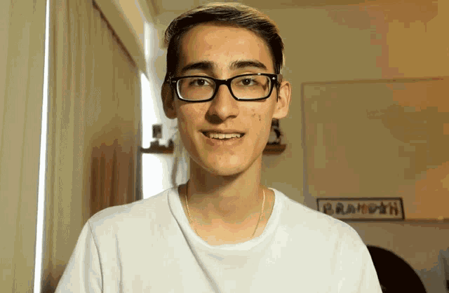 a young man wearing glasses and a white shirt has a sign on the wall that says brameth