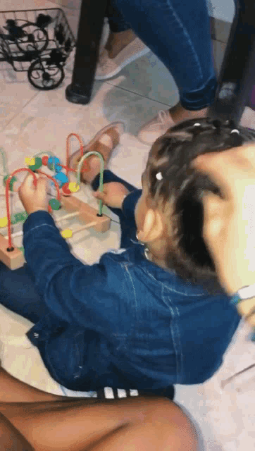 a child is playing with a wooden bead maze
