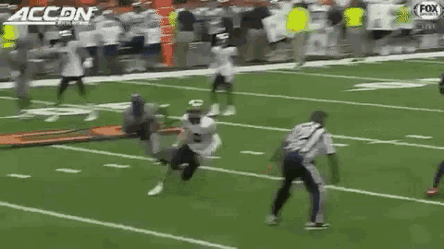 a football player is running on a field with a large letter u on the side .