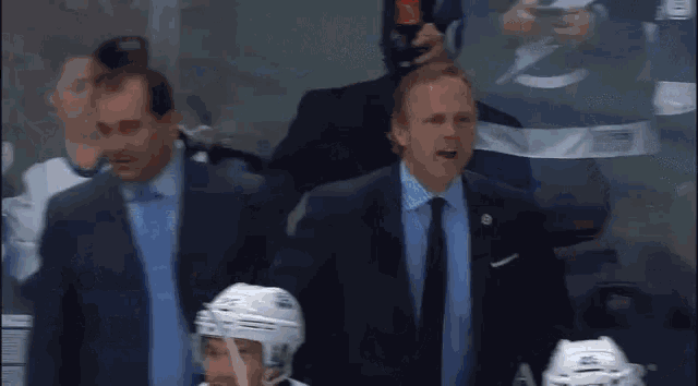 a man in a suit and tie is standing in front of a hockey team