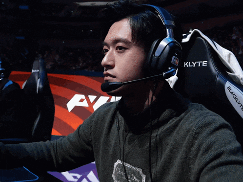 a man wearing headphones and a black klyte gaming chair