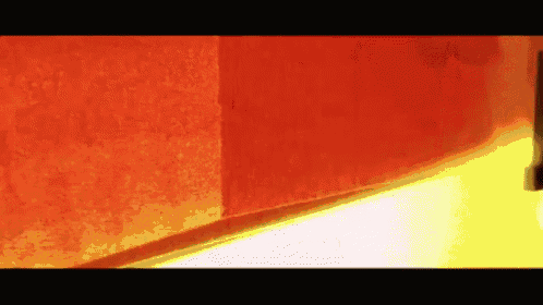 a person is standing in front of a red wall and a yellow light .