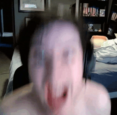 a blurry picture of a person 's face in front of a bookshelf with pictures on it