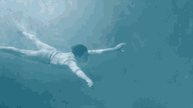 a man is swimming underwater in a blue pool