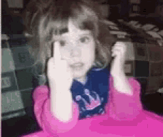 a little girl is wearing a pink sweater and talking on a cell phone