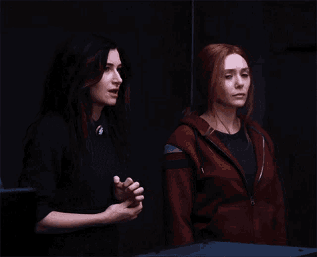 two women are standing next to each other and one is wearing a red hoodie