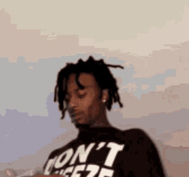 a man with dreadlocks is wearing a black shirt that says `` i 'm not a fan '' .
