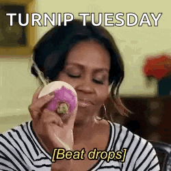 a woman in a striped shirt is holding a purple radish in her hand .