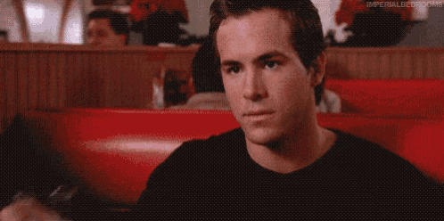 a man is sitting in a red booth in a diner looking at the camera .
