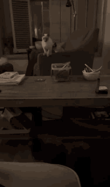a blurred image of a person sitting at a table with a bowl of spoons on it
