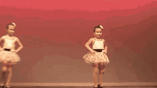 a little girl is dancing on a stage in front of a red background