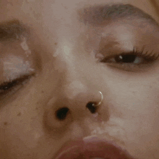 a close up of a woman 's face with a nose ring