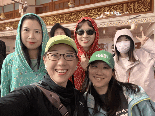 a group of women posing for a picture with one wearing a hat that says positive