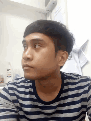 a young man wearing a striped shirt looks up at something