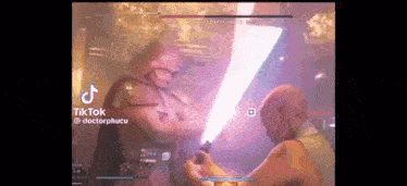 a man is holding a lightsaber in a video game while another man is holding a lightsaber in a video game .