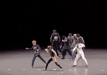 a group of people are dancing on a stage in a dark room .