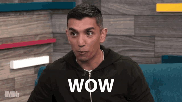 a man sitting on a couch with the word wow written on the screen