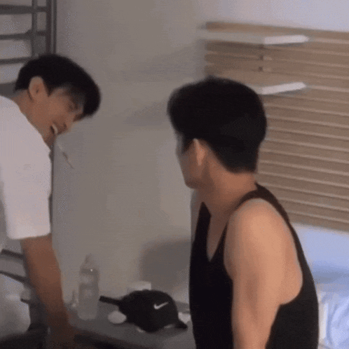 two men are standing next to each other in a room and one has a nike hat on