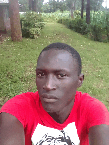 a young man wearing a red shirt with a picture of a man on it